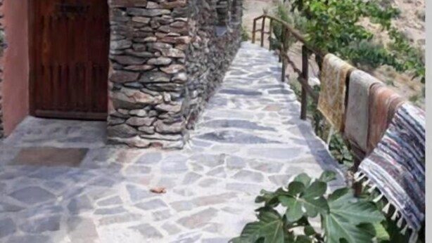 A stone building with a wooden door and a stone pathway leading to it. - Refugio Arrabales de la Alpujarra - Hostel (La Taha)