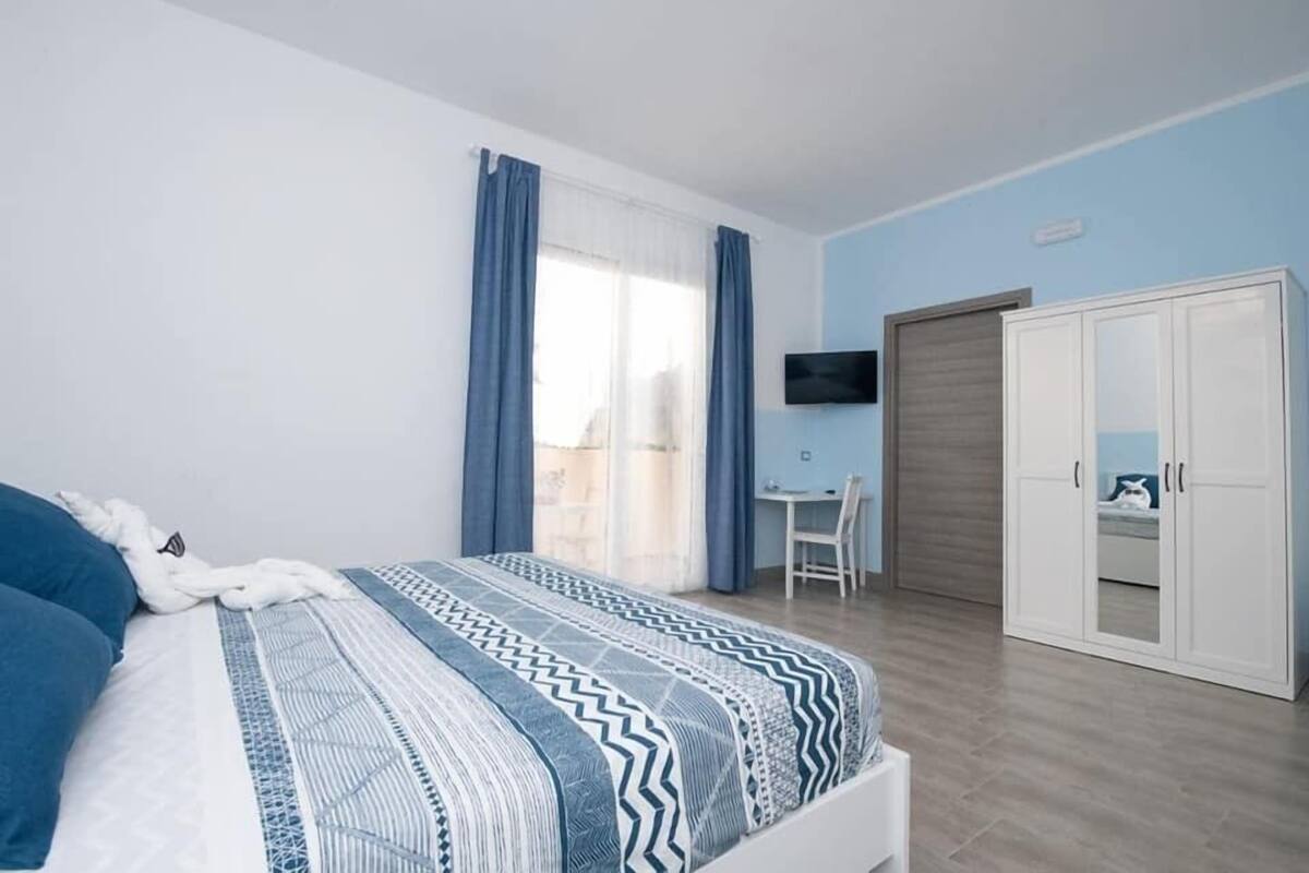 A bedroom with a bed, a desk, a TV, and a wardrobe.