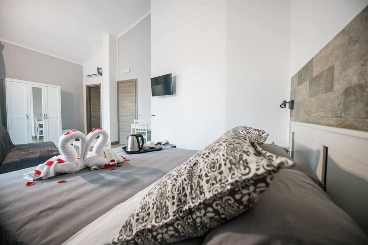 A hotel room with a bed, a television, a wardrobe, and a coffee machine.