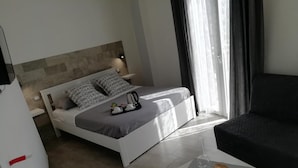 A modern bedroom with a bed, bedside table, and a small table with decorative items. - Dove sorge il sole (Custonaci)
