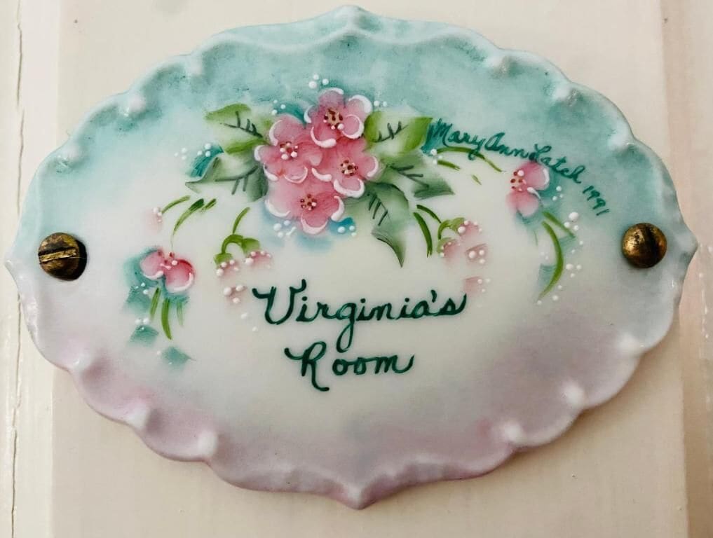 A decorative plaque with floral patterns and the text 'Virginia's Room' and 'Maryam's 1991'.