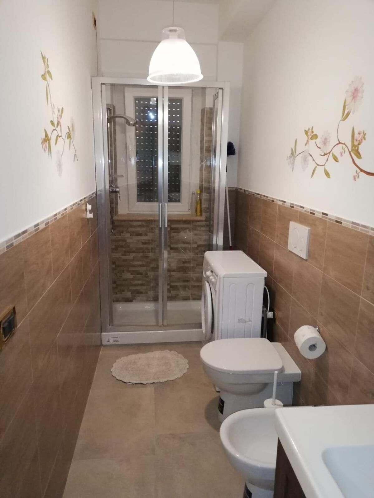 Un baño con cabina de ducha de vidrio, inodoro, lavamanos y cortina de ducha.
