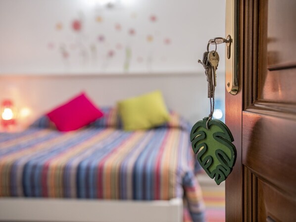 A bedroom with a bed, colorful pillows, and a keychain on the door. - La Casa delle Stagioni (L'Aquila)