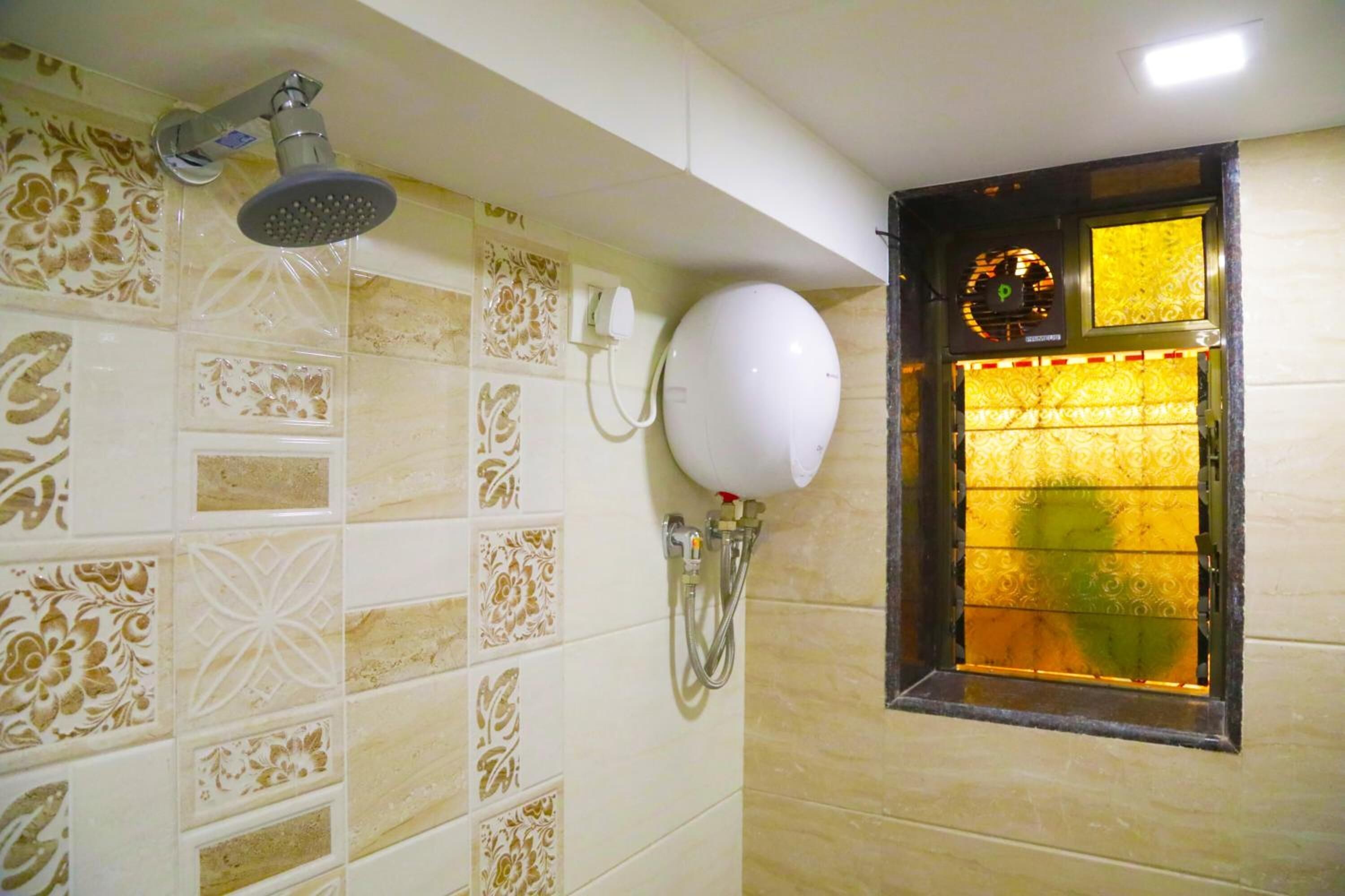 A bathroom with patterned tiles, a handheld showerhead, a wall-mounted toilet paper holder, and a window with a decorative grille.