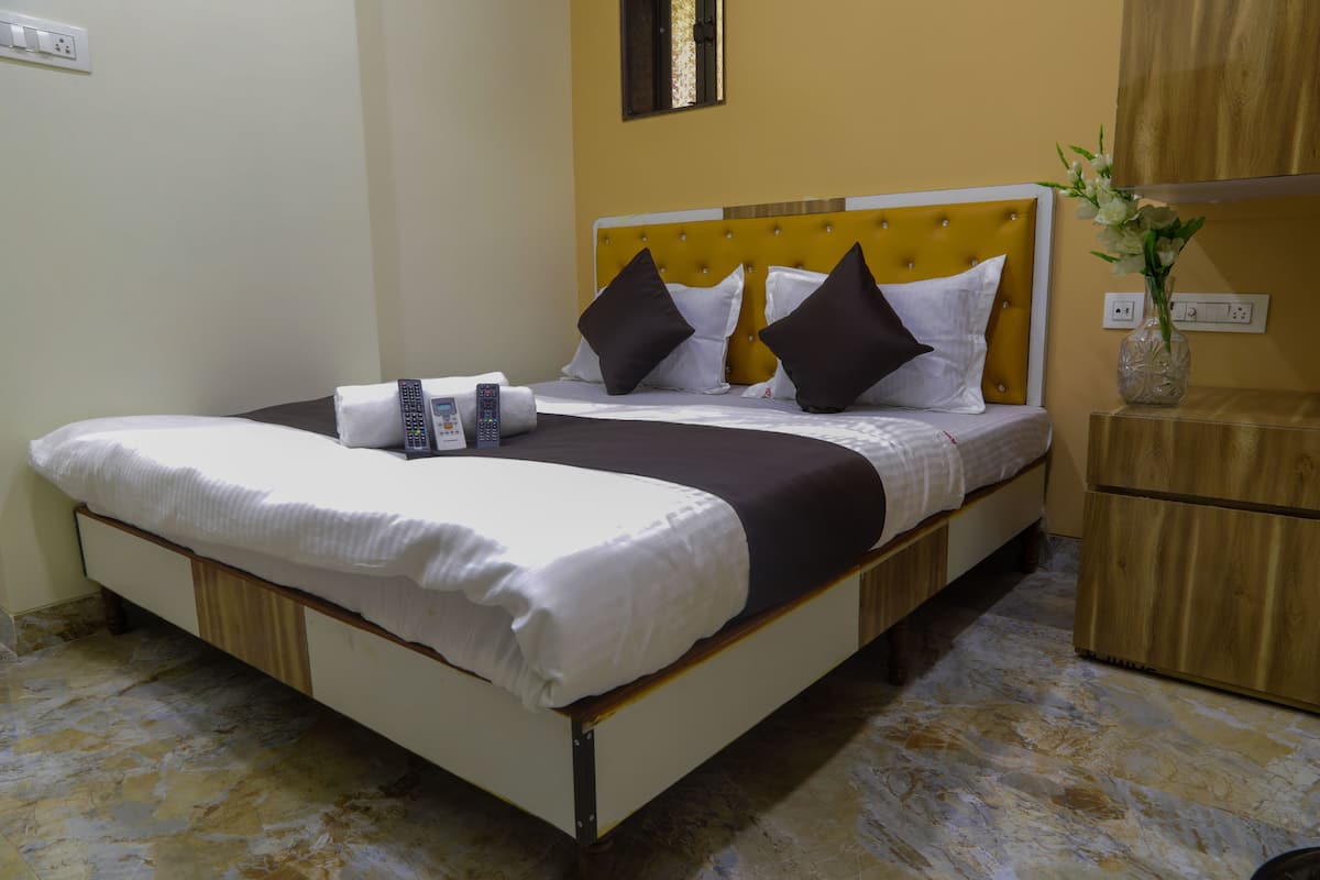 A neatly made bed with a white and black bedspread, two pillows, and a remote control on the side.