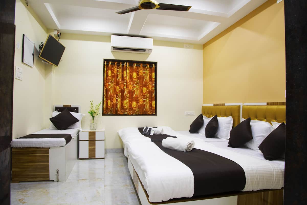 A hotel room with a bed, bedside tables, a ceiling fan, an air conditioning unit, and a painting on the wall.