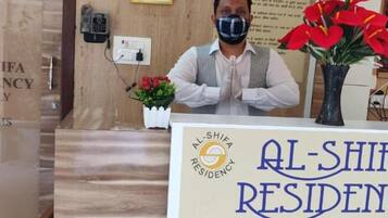 Mostrador de recepción en Al-Shifa Residency con un cartel que muestra el nombre y la información de contacto.