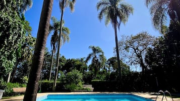 Una piscina al aire libre, sombrillas, sillones reclinables de piscina