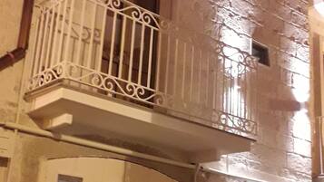 Een gebouw met een balkon, een deur en een afvalbak.