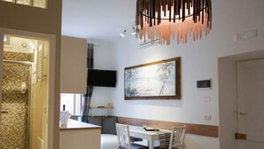 Een moderne keuken met een eethoek, een aan de muur bevestigde televisie en een schilderij boven de tafel.