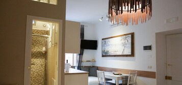 Una cocina moderna con comedor, un televisor en la pared y un cuadro sobre la mesa.
