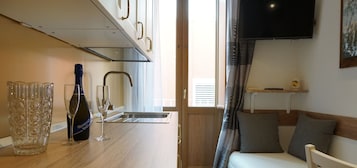 Una kitchenette compacta con un lavamanos de acero inoxidable, una copa de vino y una botella.