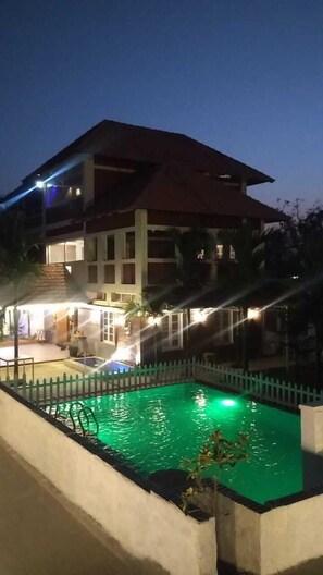 Un hôtel à plusieurs étages doté d’une piscine, le tout entouré d’une clôture blanche.