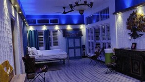 A room with a bed, a desk, and a chair. There are curtains on the windows and a chandelier on the ceiling. - Kimberly By Jade (Kunigal)