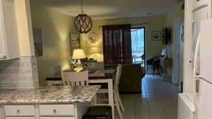 Une cuisine avec des armoires blanches, un comptoir en granit et un ventilateur de plafond.
