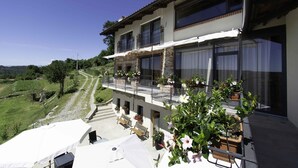 A two-story building with a balcony, outdoor seating, and potted plants. - Cascina Montiglio (Quagliuzzo)