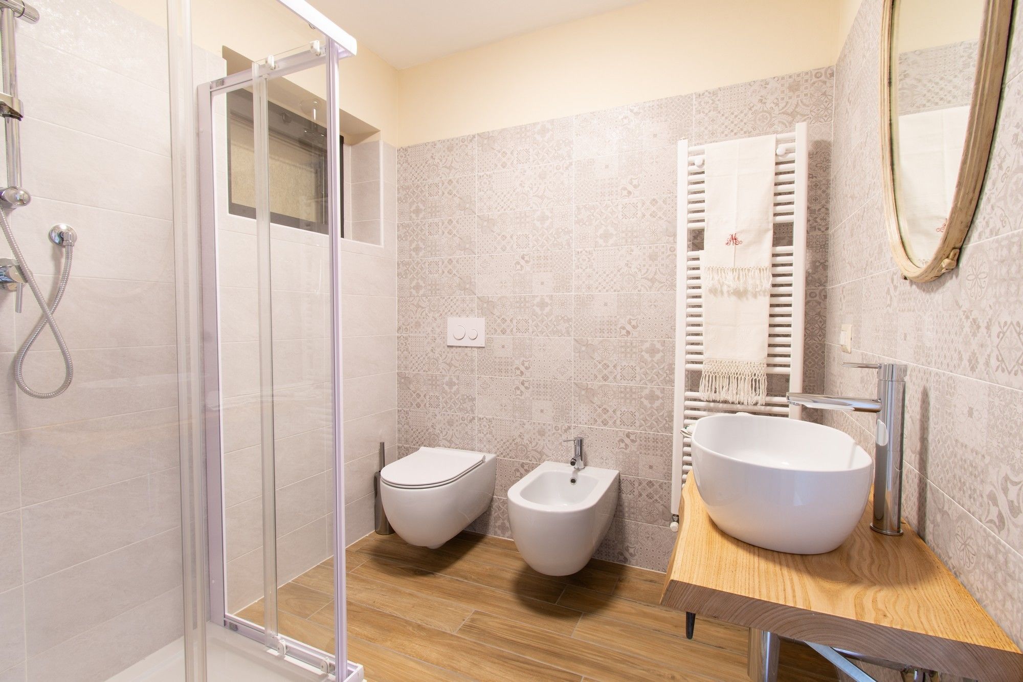 Een moderne badkamer met een douchecabine, een bidet, een ruime wastafel en een handdoekrek.