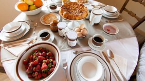 A breakfast table set with plates, bowls, cups, and a variety of food items including fruits, eggs, and pastries. - Cascina Montiglio (Quagliuzzo)