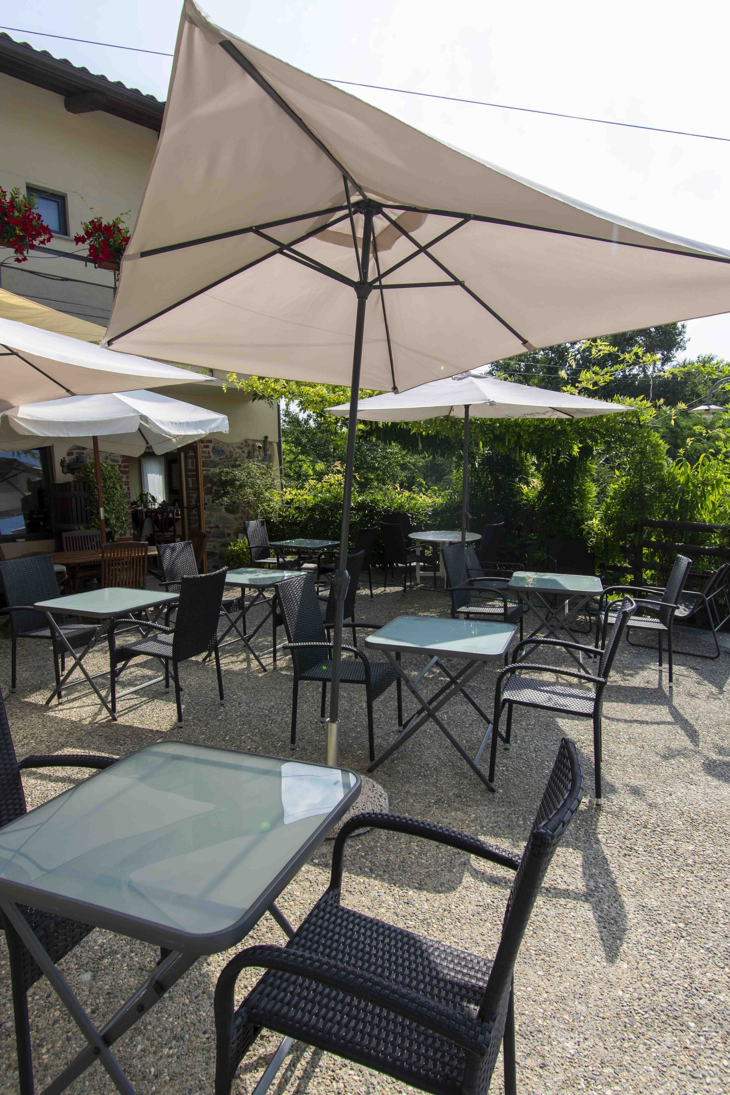 An outdoor patio area with tables and chairs, some shaded by umbrellas.