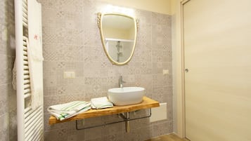 Un baño con un lavamanos blanco, un espejo y azulejos estampados.