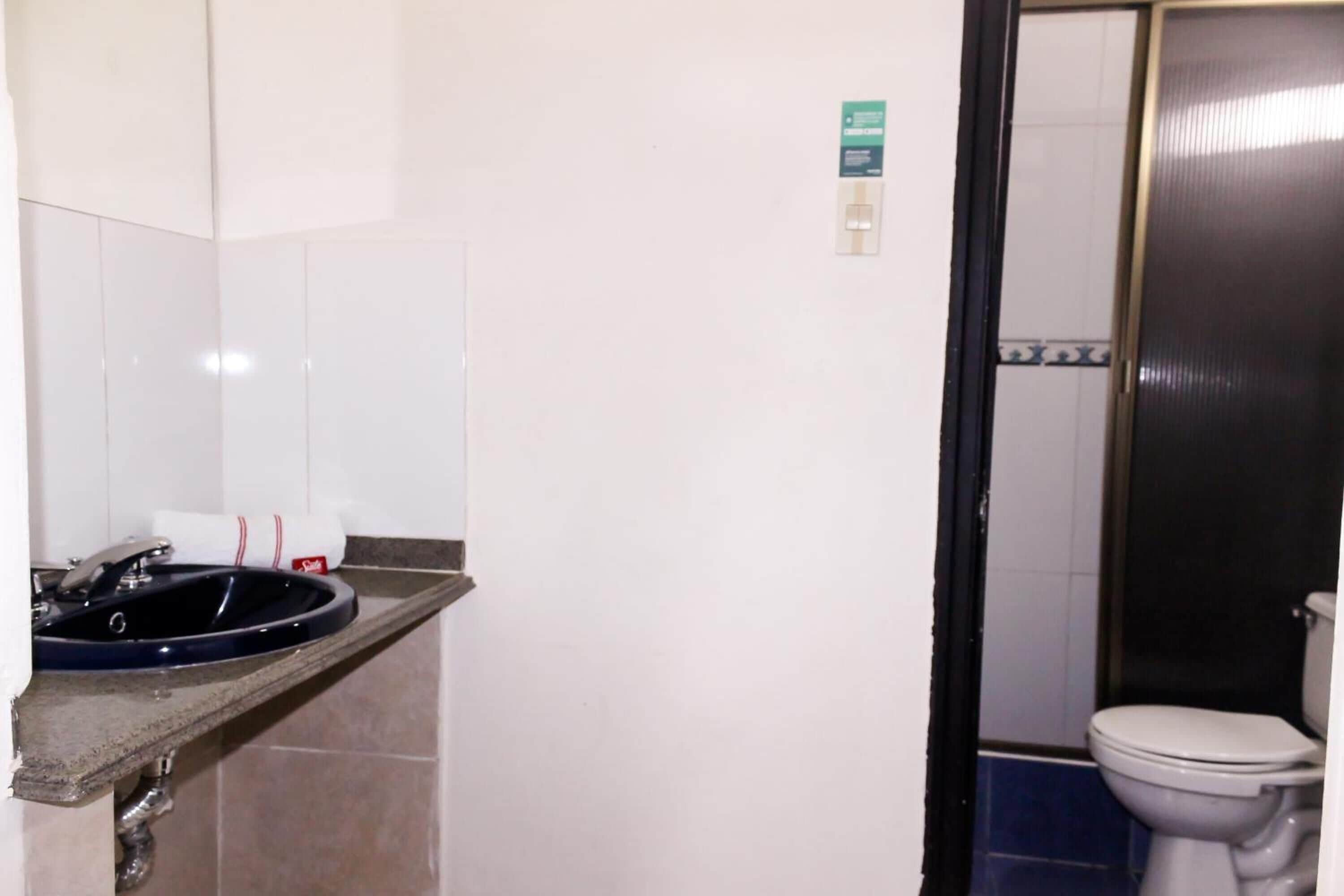 Un bagno con lavandino, WC e una porta che dà su un'altra stanza.