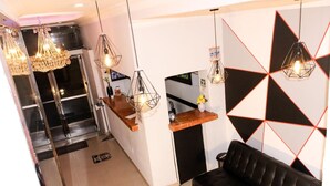 A reception area with a black leather sofa, a wooden reception desk, and geometric wall art.