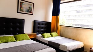 A hotel room with two beds, a nightstand, a framed picture on the wall, and a window with curtains.