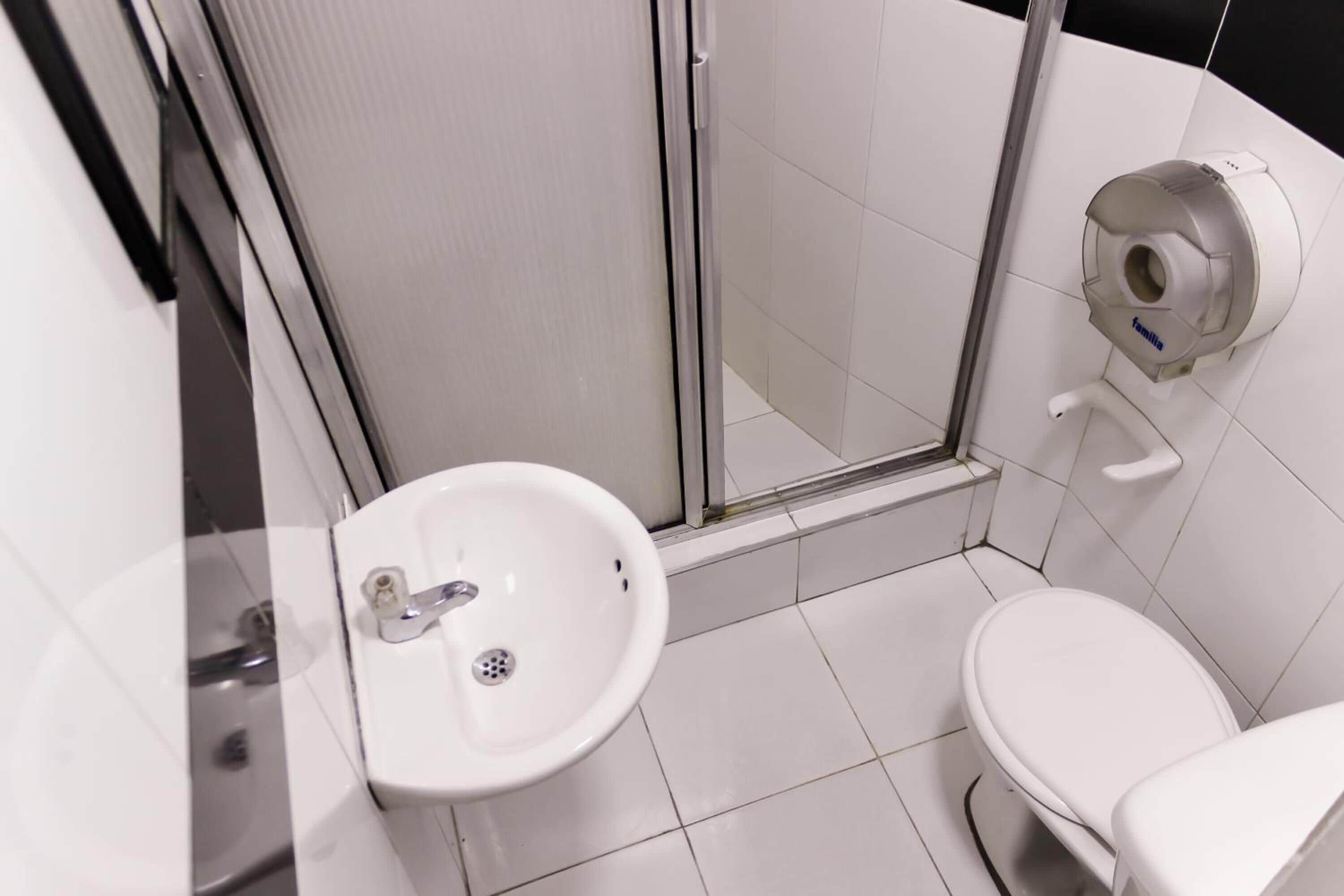 A modern bathroom with a glass-enclosed shower, a white sink, and a toilet.