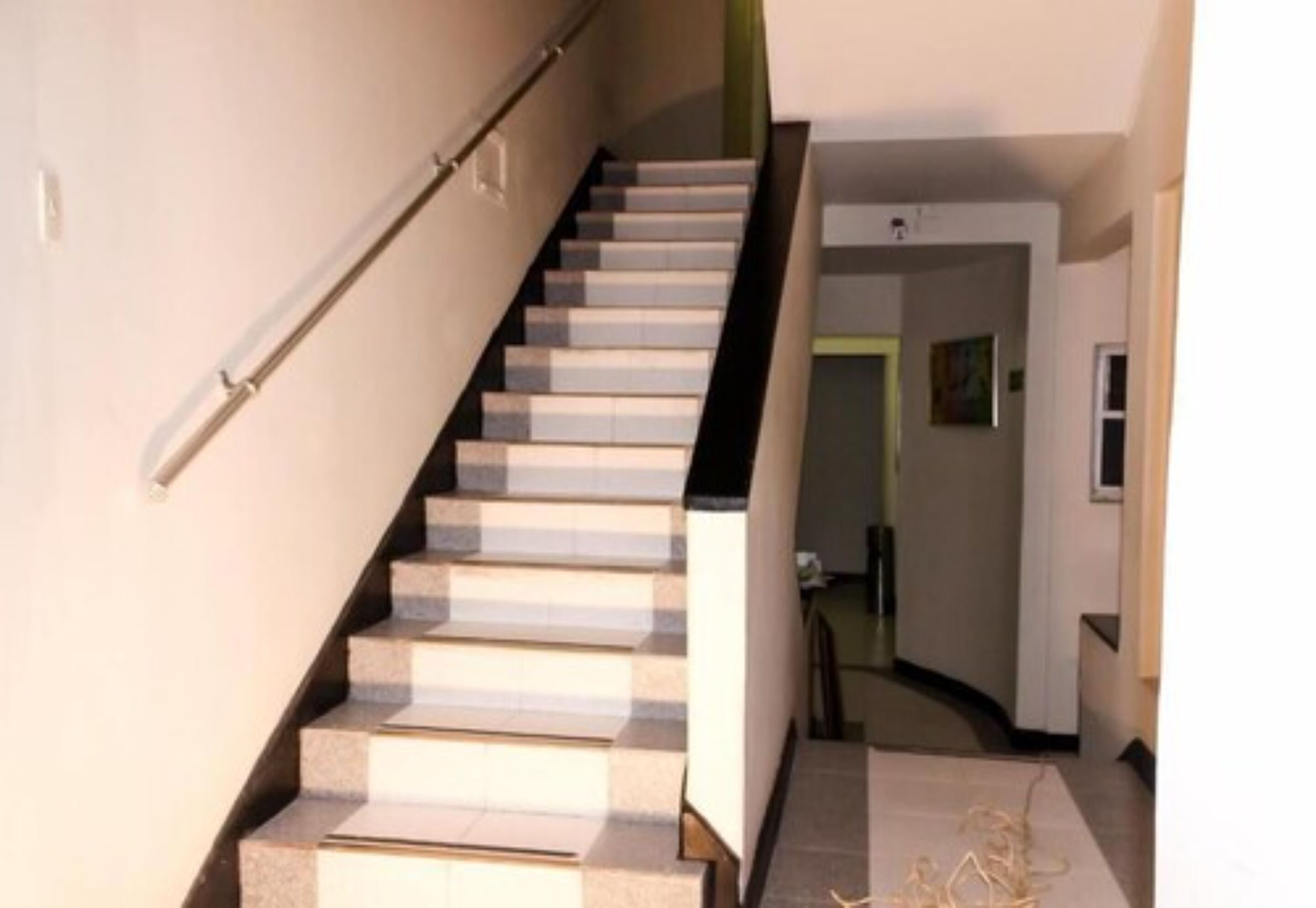 A staircase with a handrail, leading to a landing with a door and a small window.