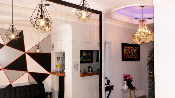 A modern reception area with a black sofa, geometric wall art, and a chandelier.