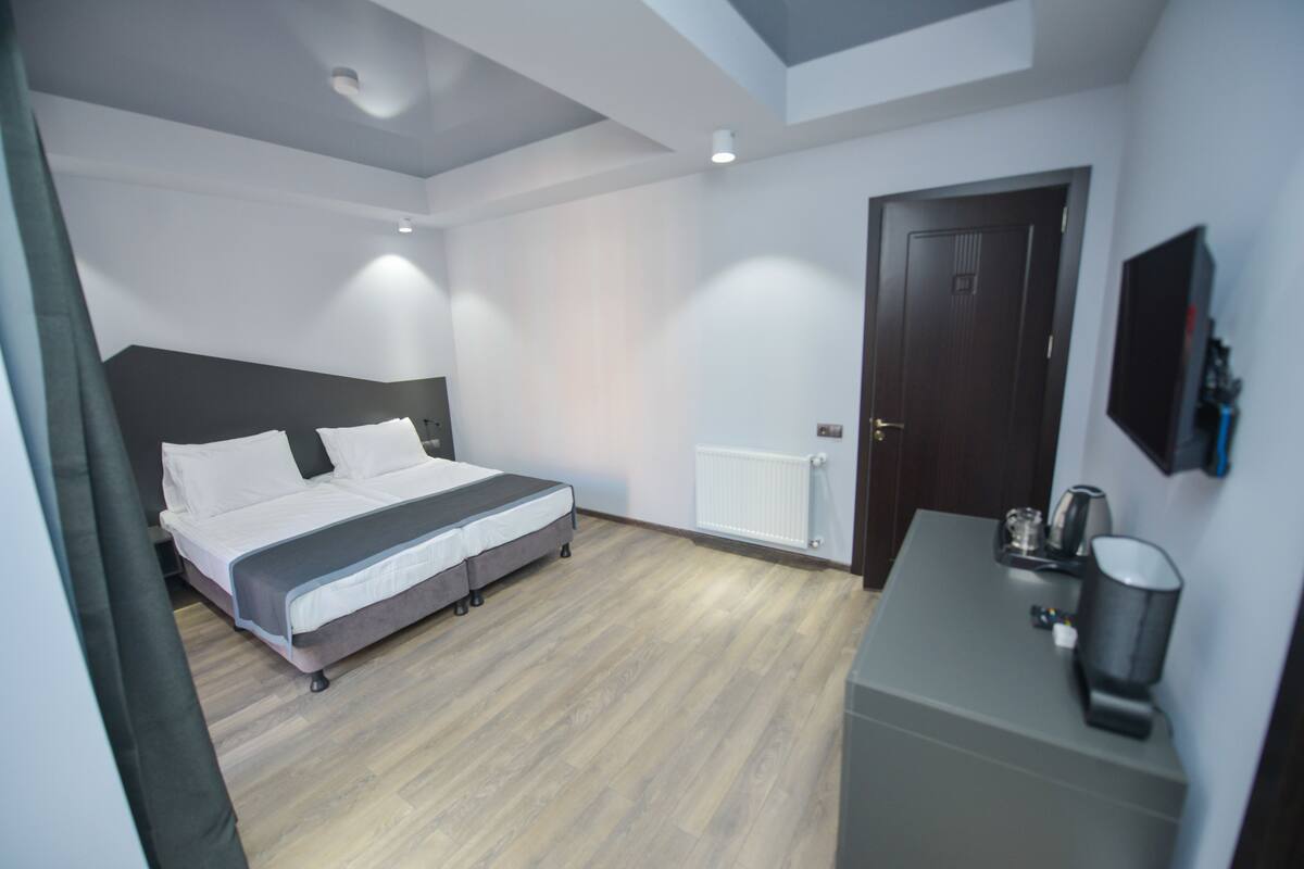 A modern bedroom with a bed, bedside table, and a door.