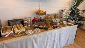 Une table de buffet proposant une variété d’aliments, notamment des pains, des fruits et des condiments.