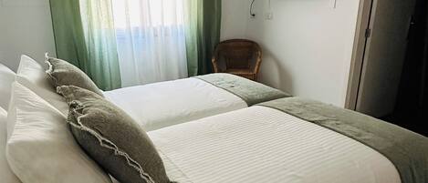 A hotel room with a bed, curtains, a television, and a chair.
