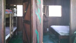 A rustic wooden room with bunk beds, a large wooden door with green leaf designs, and a bamboo ceiling. - Finca Guarumo - Hostel (Las Horquetas)