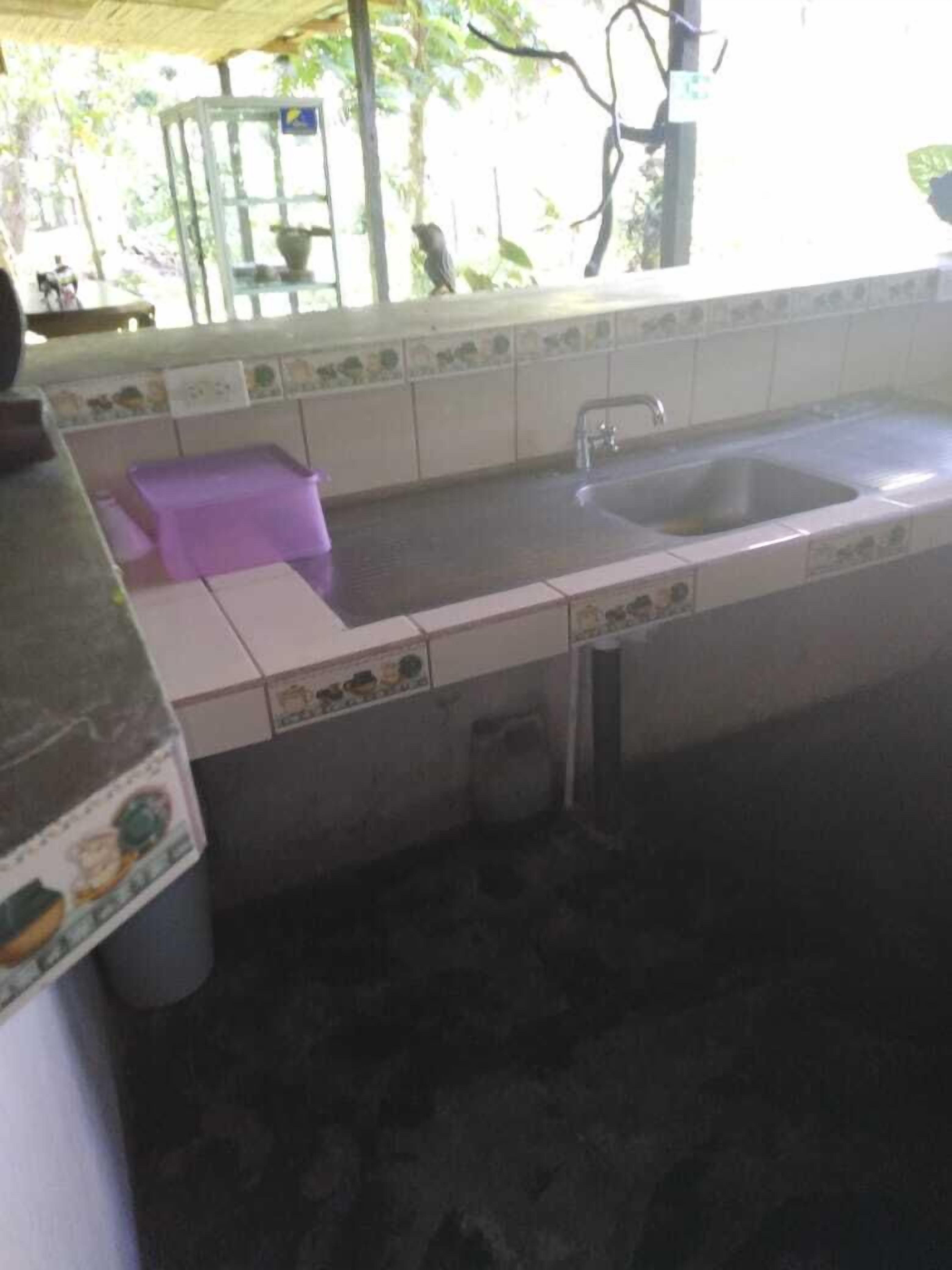 Une cuisine avec un évier, un lavabo violet et des murs carrelés.