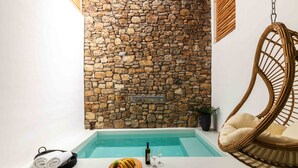 A stone wall, a wicker chair, a pool, and a towel rack with towels. - Obsession Mykonos (Mykonos)