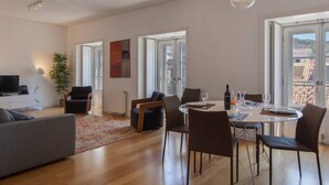 A modern living room with a dining area, large windows, and a view of the city. - Downtown Apartment Santa Justa (Lisboa)