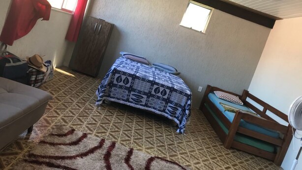 Ein Zimmer mit einem Bett, einer Couch, einem Ventilator und einem Fenster mit Vorhängen.