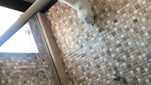 Ein Badezimmer mit Mosaikfliesen an den Wänden und einem Lüftungsgitter an der Decke.