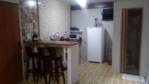 Eine kompakte Küche mit Mikrowelle, Kühlschrank und einer kleinen Essecke mit Hockstühlen.