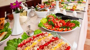 Una mesa de buffet con diversos platos, incluyendo ensaladas, sándwiches y una fuente grande de arroz con atún.