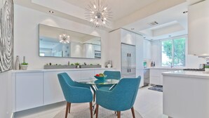 Une cuisine moderne dotée d’un îlot central, d’un coin repas avec des chaises de couleur turquoise et d’un grand miroir placé au-dessus de l’îlot.