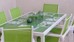 A green and white table with a floral tablecloth, surrounded by green chairs. - Villa 400m2 with swimming pool 10 min from the beach tifnit (Agadir)