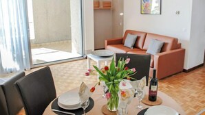 Un coin repas avec une table dressée pour deux personnes, un canapé et un tableau accroché au mur.