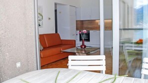 Un salon moderne avec une cloison en verre, une table à manger blanche et un canapé orange.