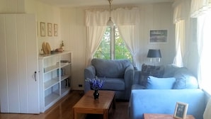 En hyggelig stue med en sofa, et sofabord og en bogreol.