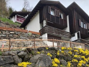 Un bâtiment à deux étages, doté d’un mur de soutènement en pierre et d’une clôture en bois.