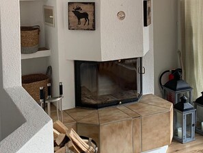 A living room with a fireplace, a wooden wall decoration, a lantern, and a basket on a shelf.