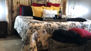 Un dormitorio con cama, almohadas, una mesita de noche y una lámpara.