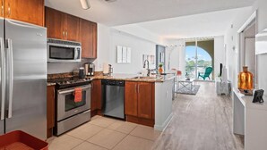 Eine moderne Küche mit Edelstahlgeräten, Holzschränken und Blick auf einen Balkon mit Sitzgelegenheit.